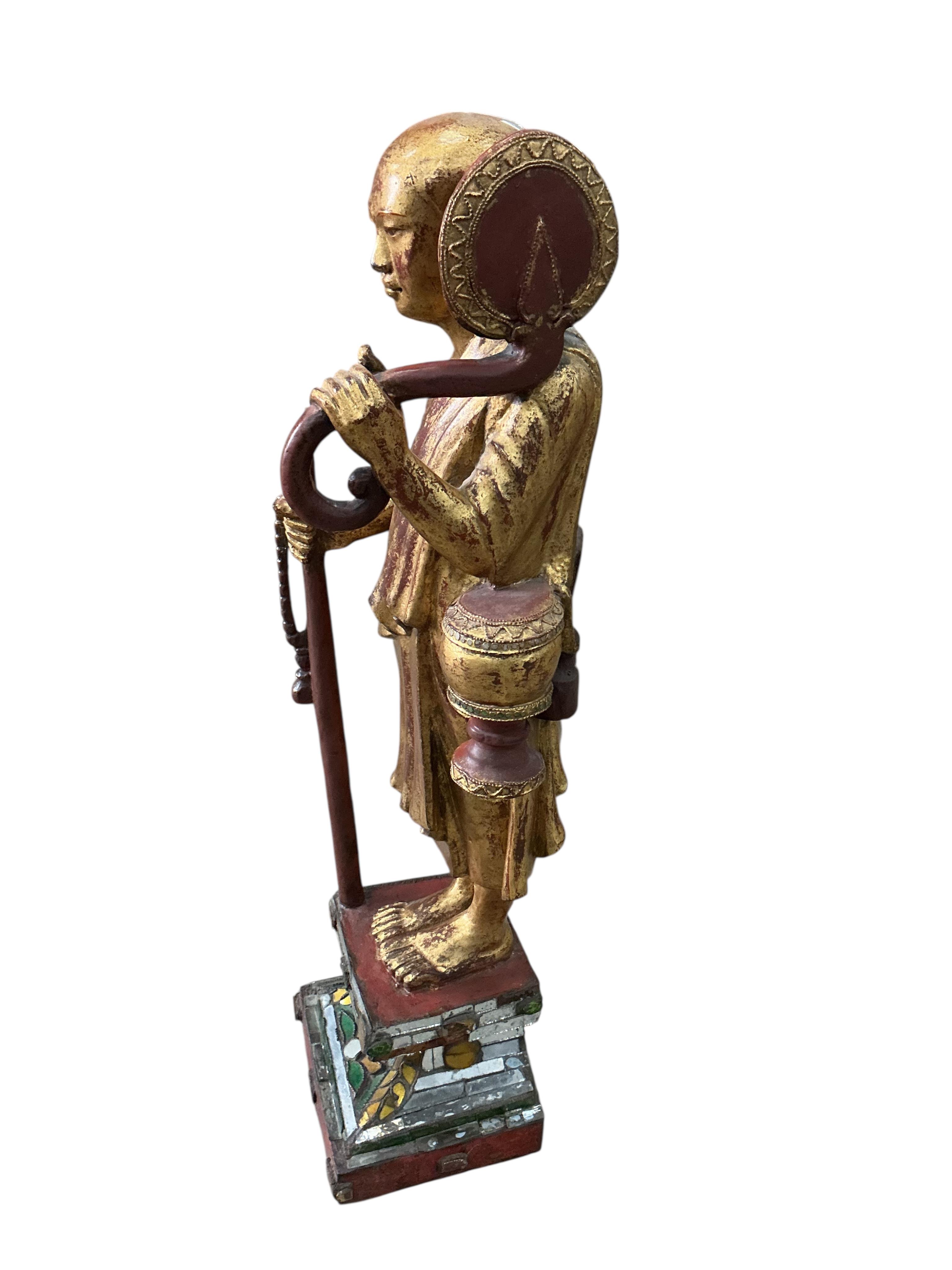 A Tibetan or Thai carved giltwood figure of a priest on a mirrored plinth, height 80cm